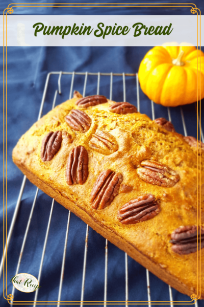 loaf of pumpkin spice bread on cooling rack with mini pumpkin