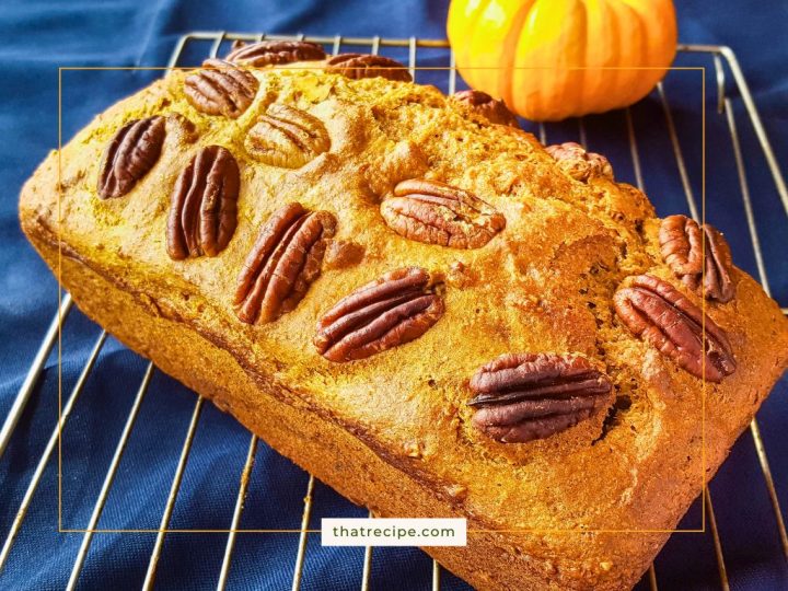 loaf of pumpkin spice bread on cooling rack with mini pumpkin