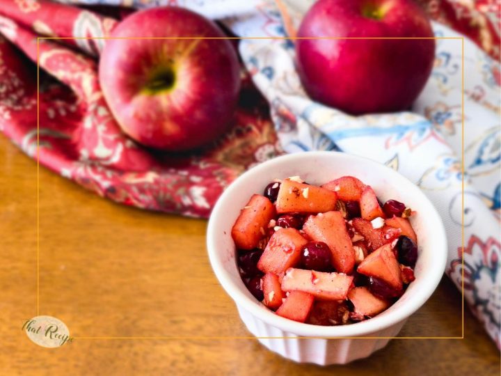 cranberry apple compote in a cup with fresh apples