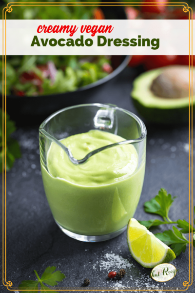 avocado salad dressing in a glass jug on a table with salad and text overlay "creamy vegan Avocado Salad Dressing"