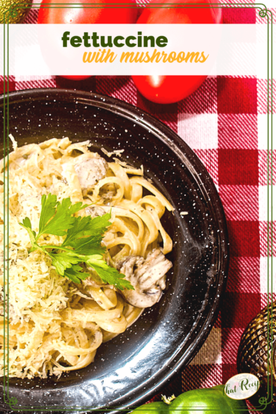 fettucine and mushrooms on a black plate on a red and white checked table cloth.