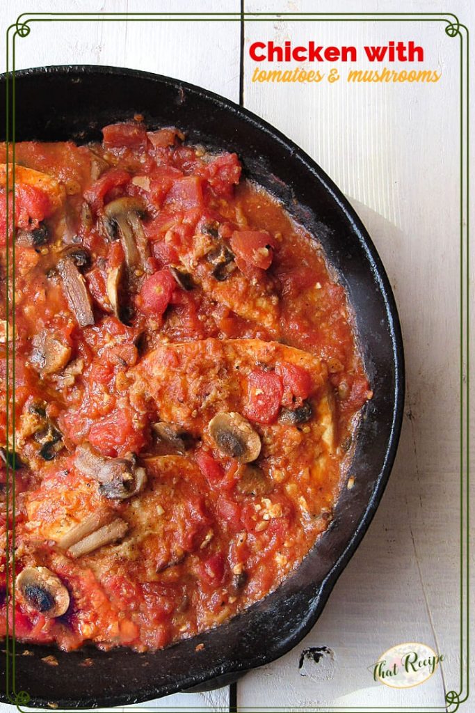 Cast iron skillet filed with chicken stewd in tomatoes with mushrooms