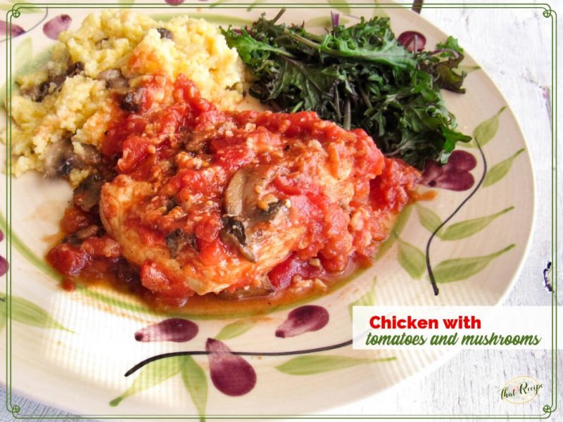 chicken with tomatoes and mushrooms on a plate with polenta and kale