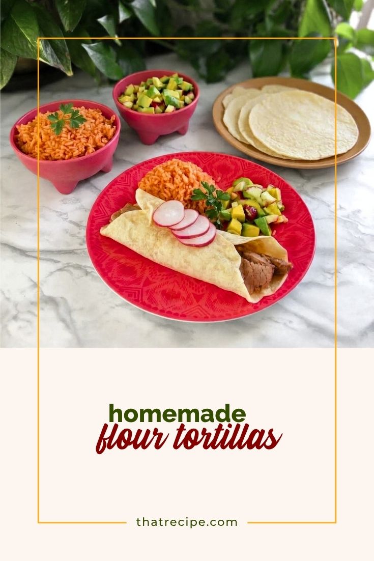 steak burrito on a plate with Mexican rice, avocado salsa and flour tortillas in the background