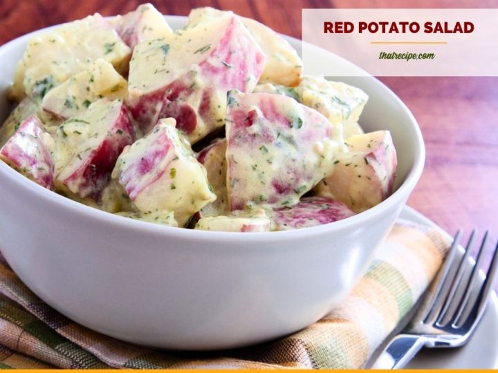 bowl of red potato salad on a table with text overlay "Creamy Dijon Potato Salad"