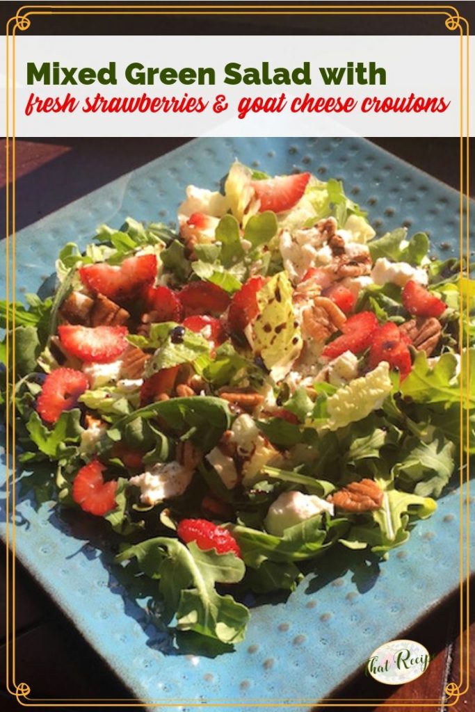 green salad with strawberries and goat cheese on a blue plate