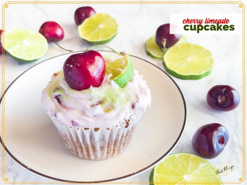 cherry limeade cupcake on a plate with fresh cherries and limes