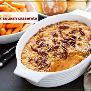squash casserole on a table with carrots and rolls.