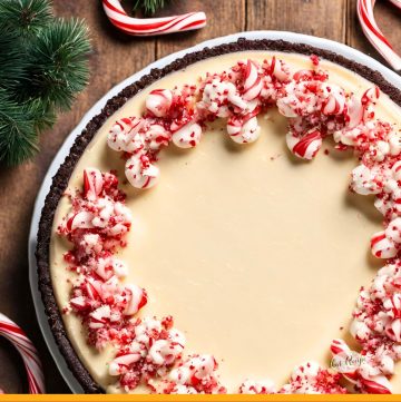 hocolate peppermint cheesecake on a plate with flocked greens and candy canes on table