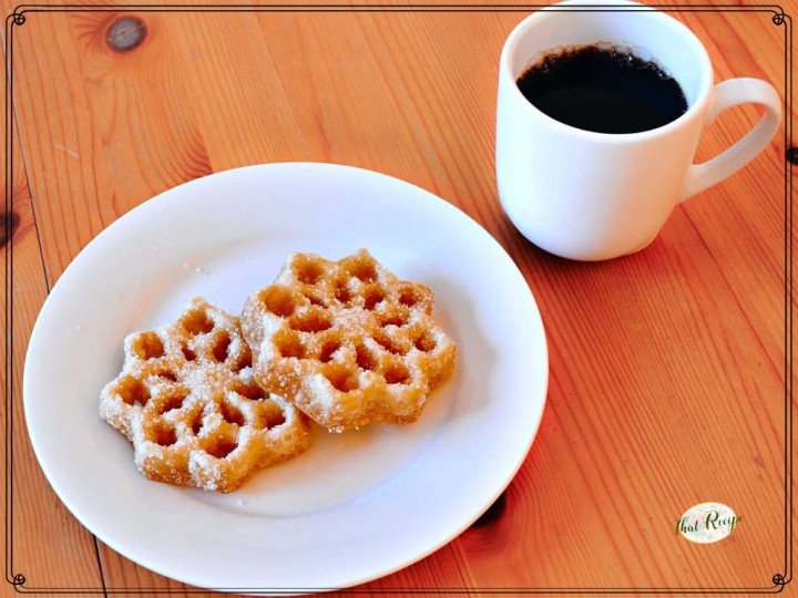 rosette cookies on a plate next to a mug of coffee