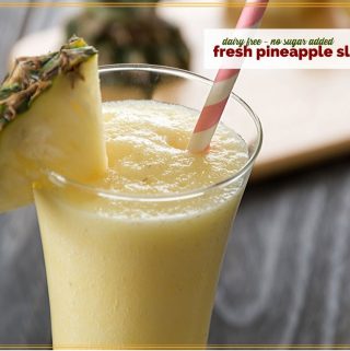 pineapple slushie on a table with sliced pineapple