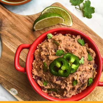 bowl of refried beans on a chopping block with limes