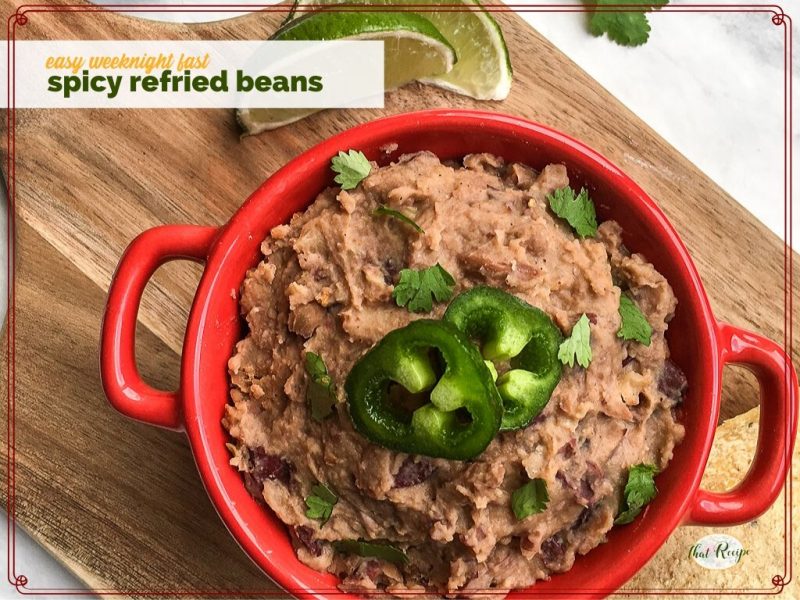 bowl of refried beans on a chopping block with limes