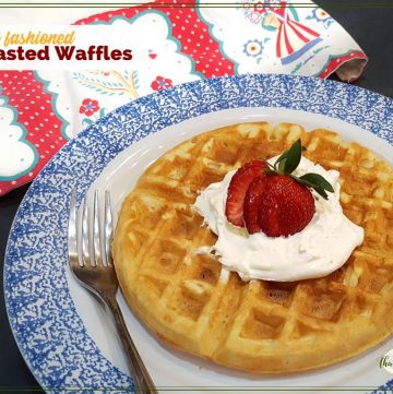 waffle on a plate topped with strawberry and whipped cream with text overlay "old fashioned yeasted waffles"