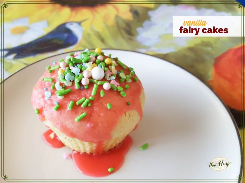cupcake with sprinkles on a plate with text overlay "vanilla fairy cakes"