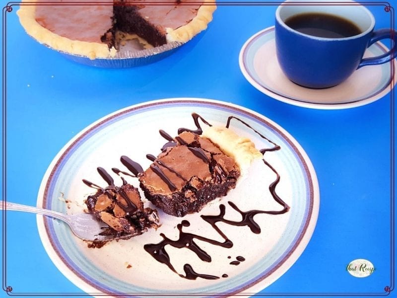 chocolate pie on a plate with cup of coffee and text overlay "fudgy brownie pie"