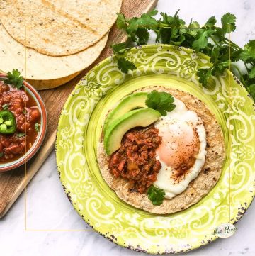 huevos rancheros on a plate with tortillas and a bowl of salsa