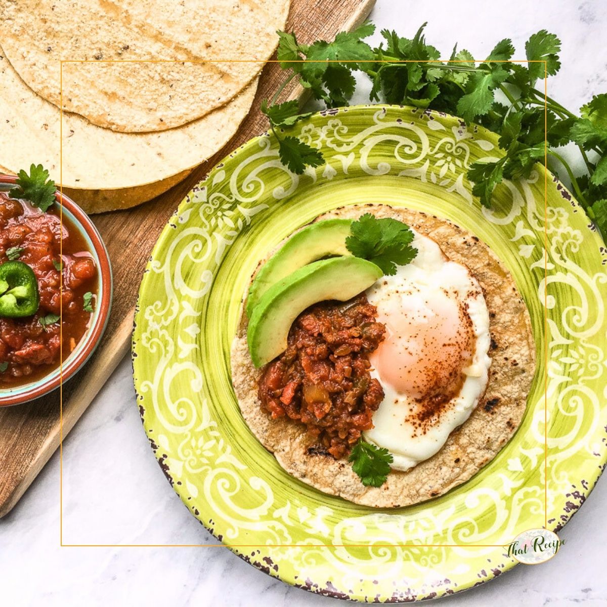 huevos rancheros on a plate with tortillas and a bowl of salsa