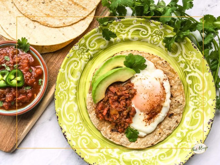 huevos rancheros on a plate with tortillas and a bowl of salsa
