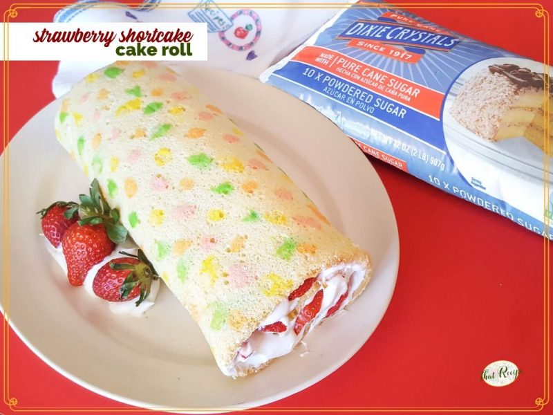 vanilla swiss cake roll with strawberries and whipped cream with text overlay "strawberry shortcake cake roll"