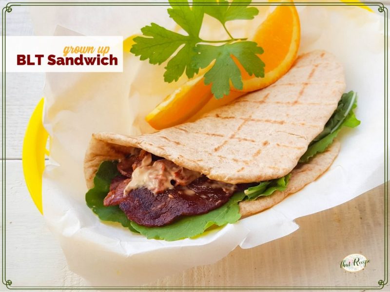 BLT pita wrap with orange slices and text overlay "grown Up BLT Sandwich"