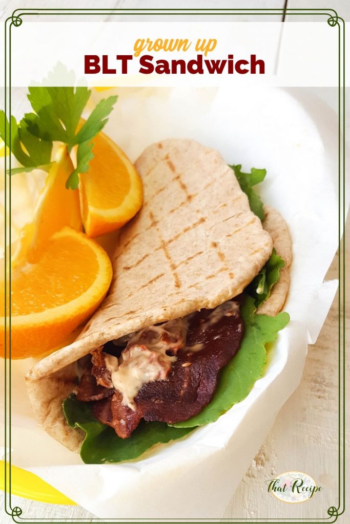 BLT pita wrap with orange slices and text overlay "grown Up BLT Sandwich"