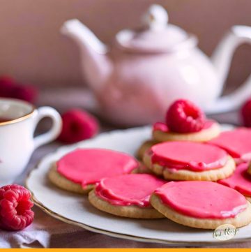 pink iced cookies on a plate with text overlay "raspberry rose sugar cookies"