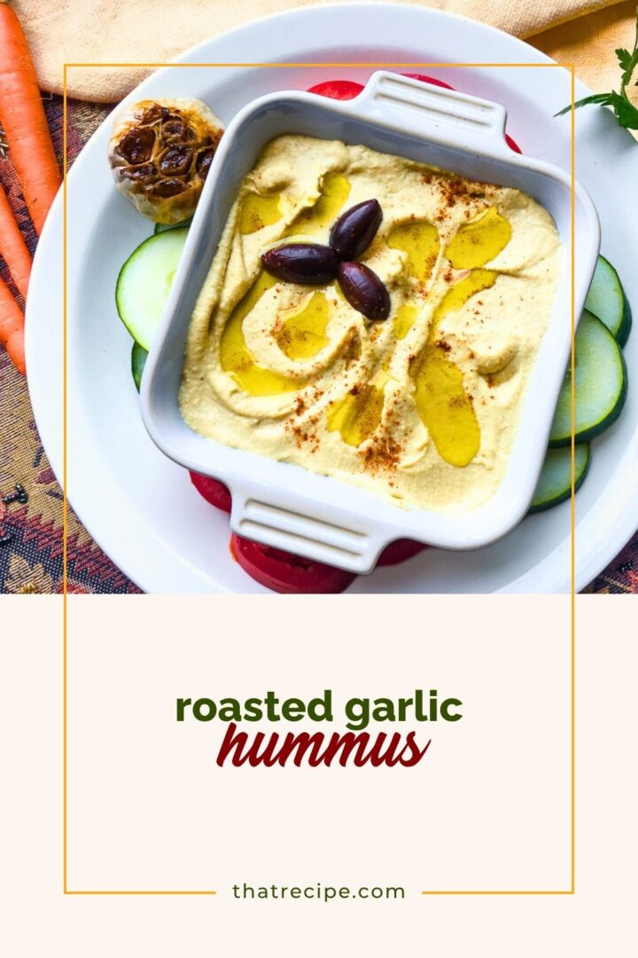 hummus in a bowl with roasted garlic head and vegetables