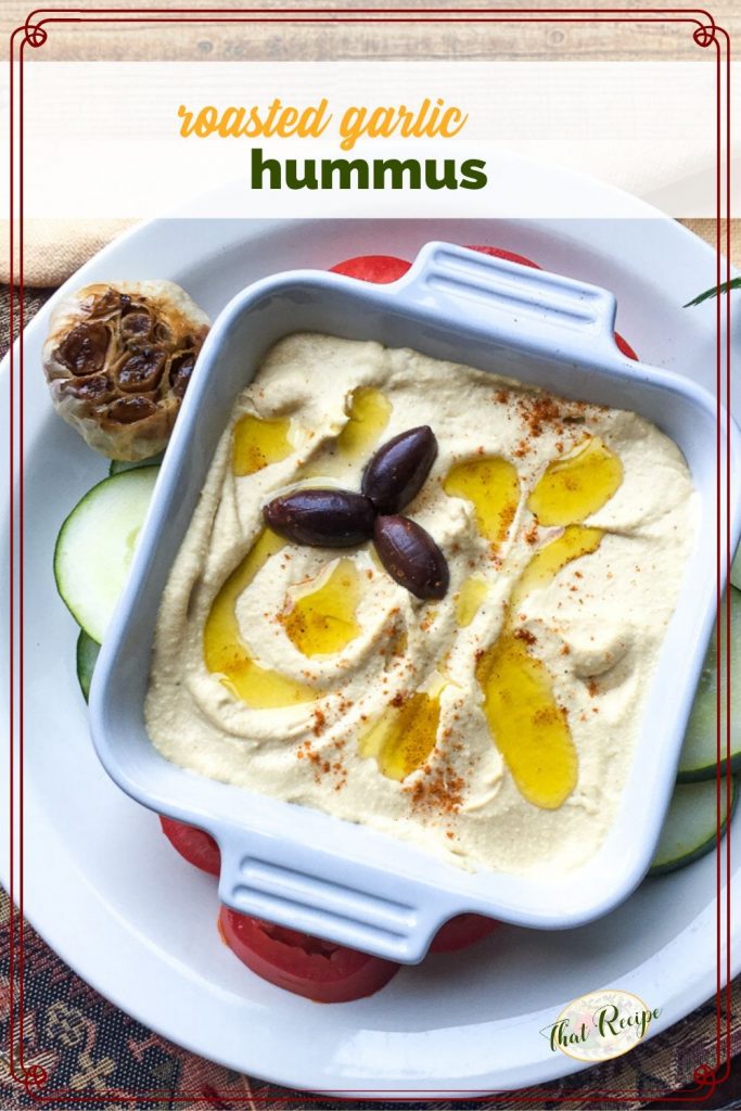 bowl of hummus with olive oil drizzle and kalamata olives and text overlay "roasted garlic hummus"