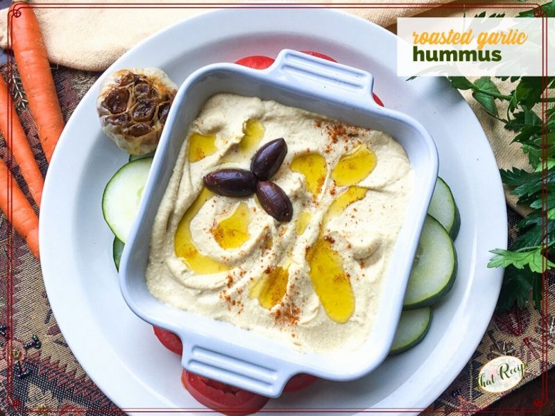 bowl of hummus with olive oil drizzle and kalamata olives and text overlay "roasted garlic hummus"