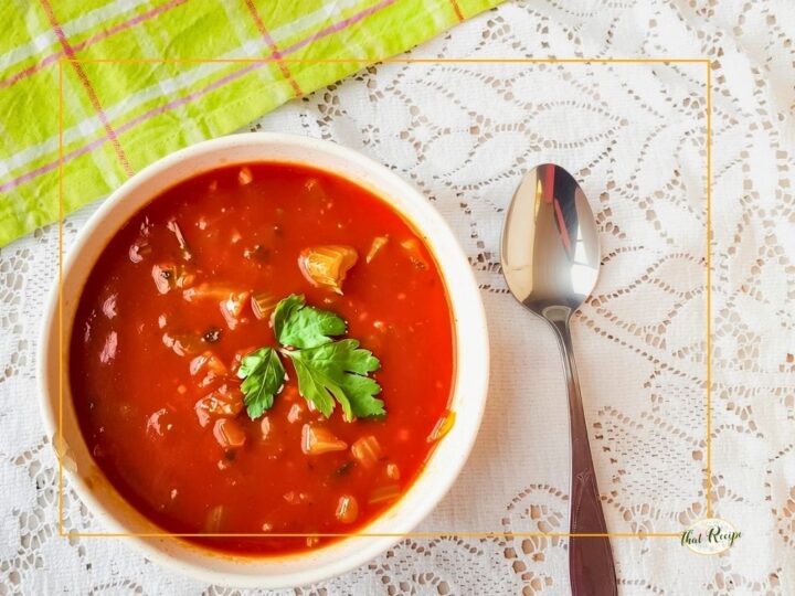 overhead view of tomato and celery soup in a bowl with a spoon