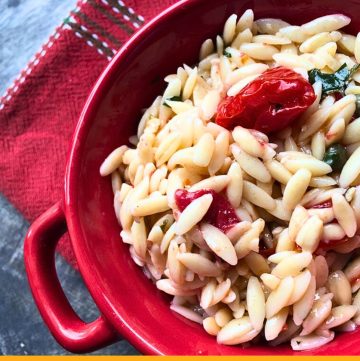 orzo pasta salad in a red bowl on blue slate with text overlay "orzo pasta salad with tomatoes and capers"