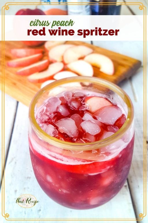 glass of red wine spritzer with peach slices on a cutting board "citrus peach red wine spritzer"