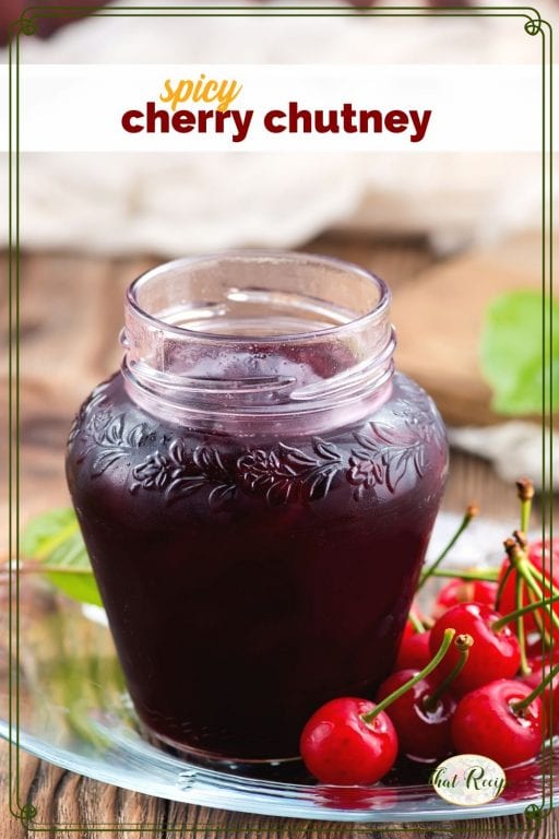 jar of cherry chutney with with fresh cherries and text overlay "spicy cherry chutney"