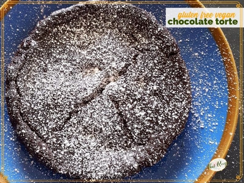 chocolate torte on a blue plate covered in powdered sugar with text "gluen free vegan chocolate torte