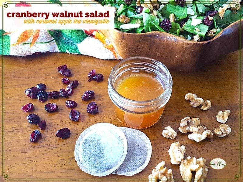 salad dressing in a jar with cranberries, walnuts, tea bags and a salad bowl around it and text overlay "cranberry walnut salad with caramel apple tea dressing"