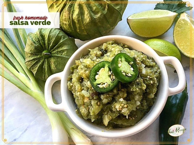 bowl of salsa verde with limes, tomatillos, peppers and onions surrounding it and text overlay "fresh homemade salsa verde"