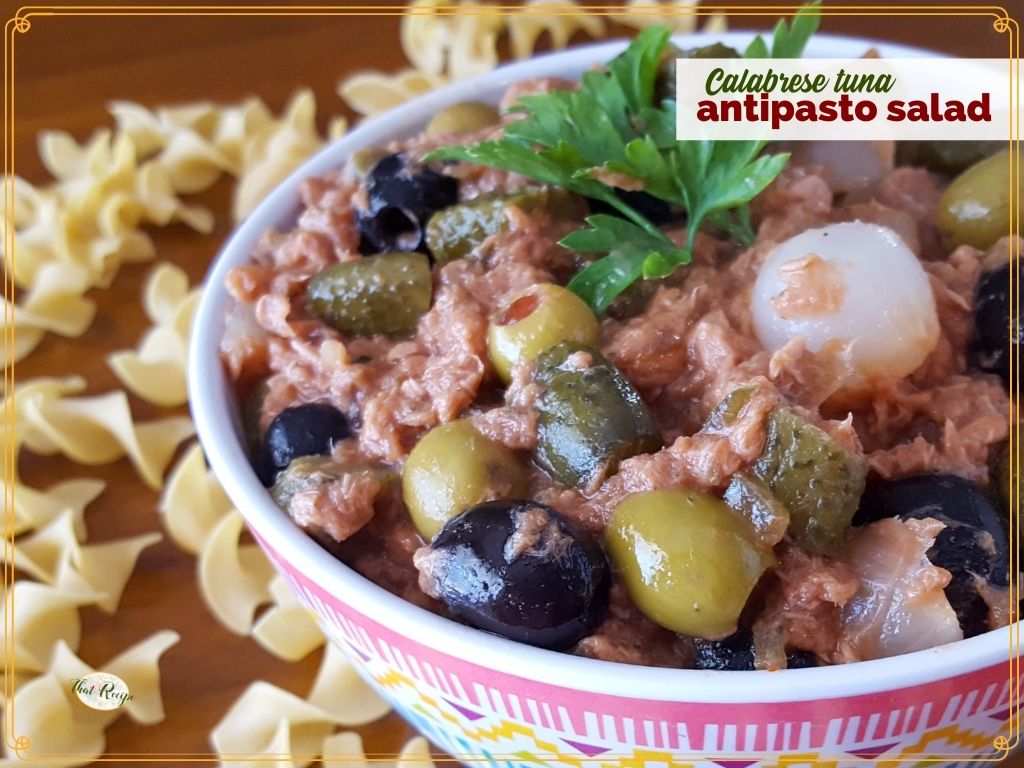 bowl of antipasto salad on a table surrounded by pasta with text overlay "Calabrese tuna Antipasto Salad"