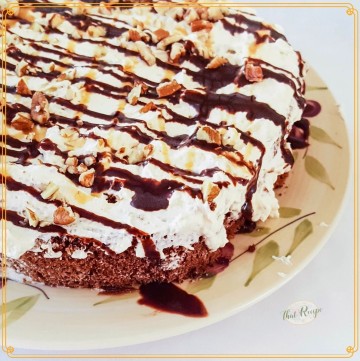 chocolate cake topped with whipped cream chocolate sauce and nuts