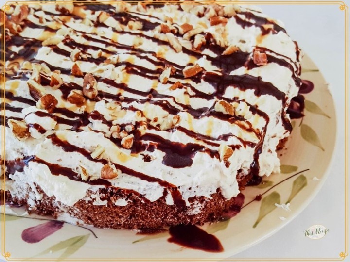 chocolate cake topped with whipped cream chocolate sauce and nuts