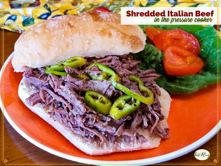 shredded beef sandwich on a plate with lettuce, tomatoes and peppers with text overlay "Shredded Italian Beef in the pressure cooker"