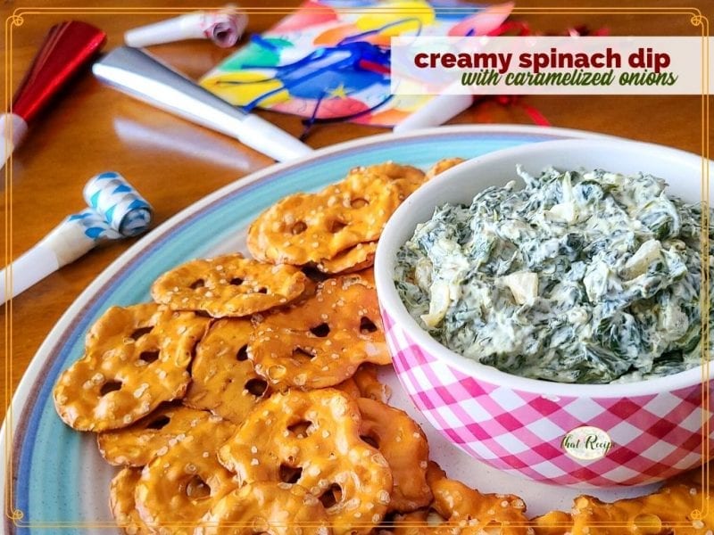 spinach dip in a bowl with pretzel crackers around it and text overlay "creamy spinach dip with caramelized onions"