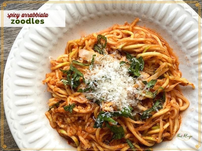 zucchini noodles with pasta sauce and parmesan on a plate with text overlay "spicy Arrabbiata Zoodles"