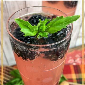 sparkling cocktails in champagne flutes with text "blackberry basil prosecco punch"