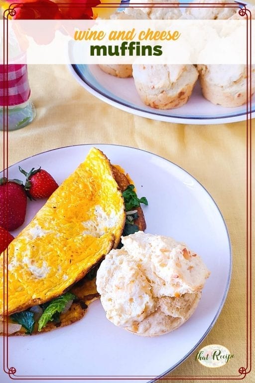 muffin on a plate with spinach omelet and fresh fruit and text overlay "wine and cheese muffins"