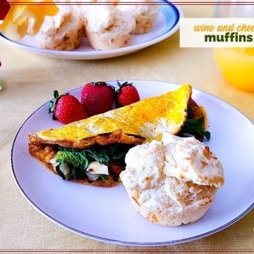muffin on a plate with spinach omelet and fresh fruit and text overlay "wine and cheese muffins"
