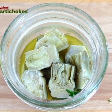 baby artichokes in a jar with text overlay "marinated baby artichokes"