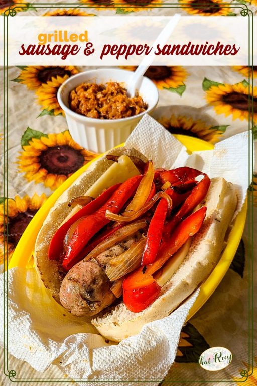 Italian sausage and pepper sandwich on a table with baked beans and text overlay "grilled sausage and pepper sandwich"