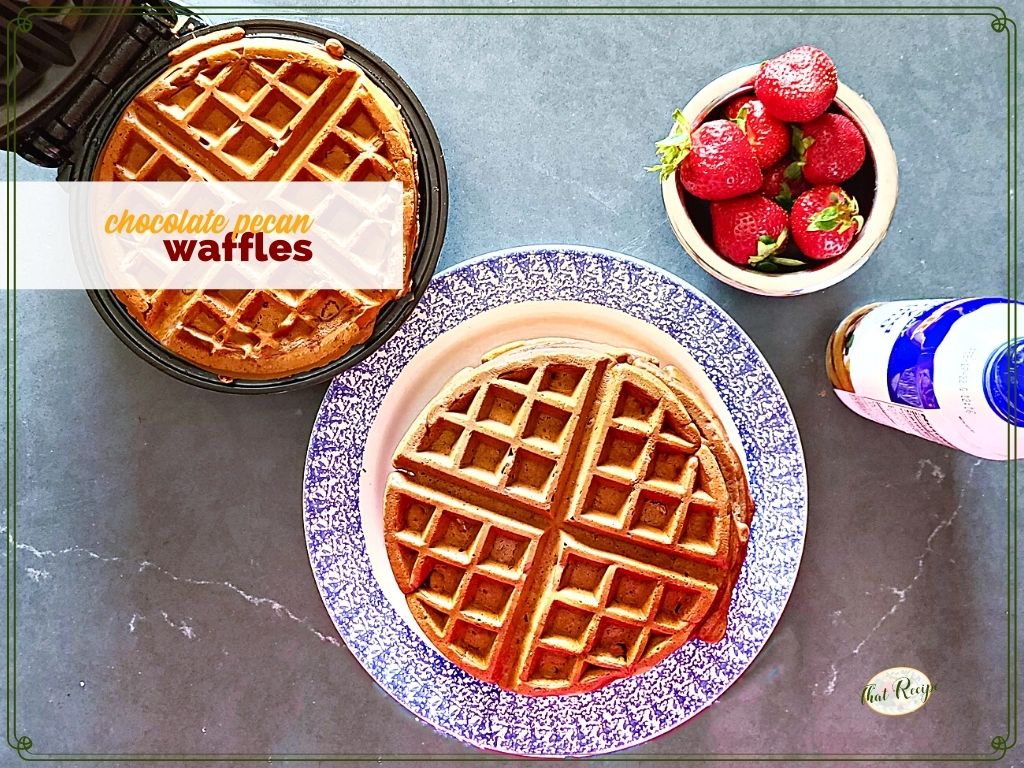 waffles on a plate and on a waffle iron with strawberries and whipped cream and text overlay "chocolate pecan waffles"
