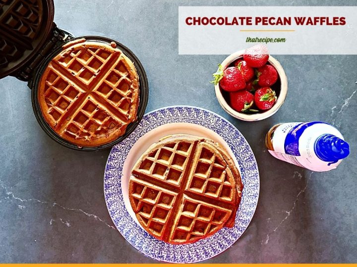 waffles on a plate and on a waffle iron with strawberries and whipped cream and text overlay "chocolate pecan waffles"
